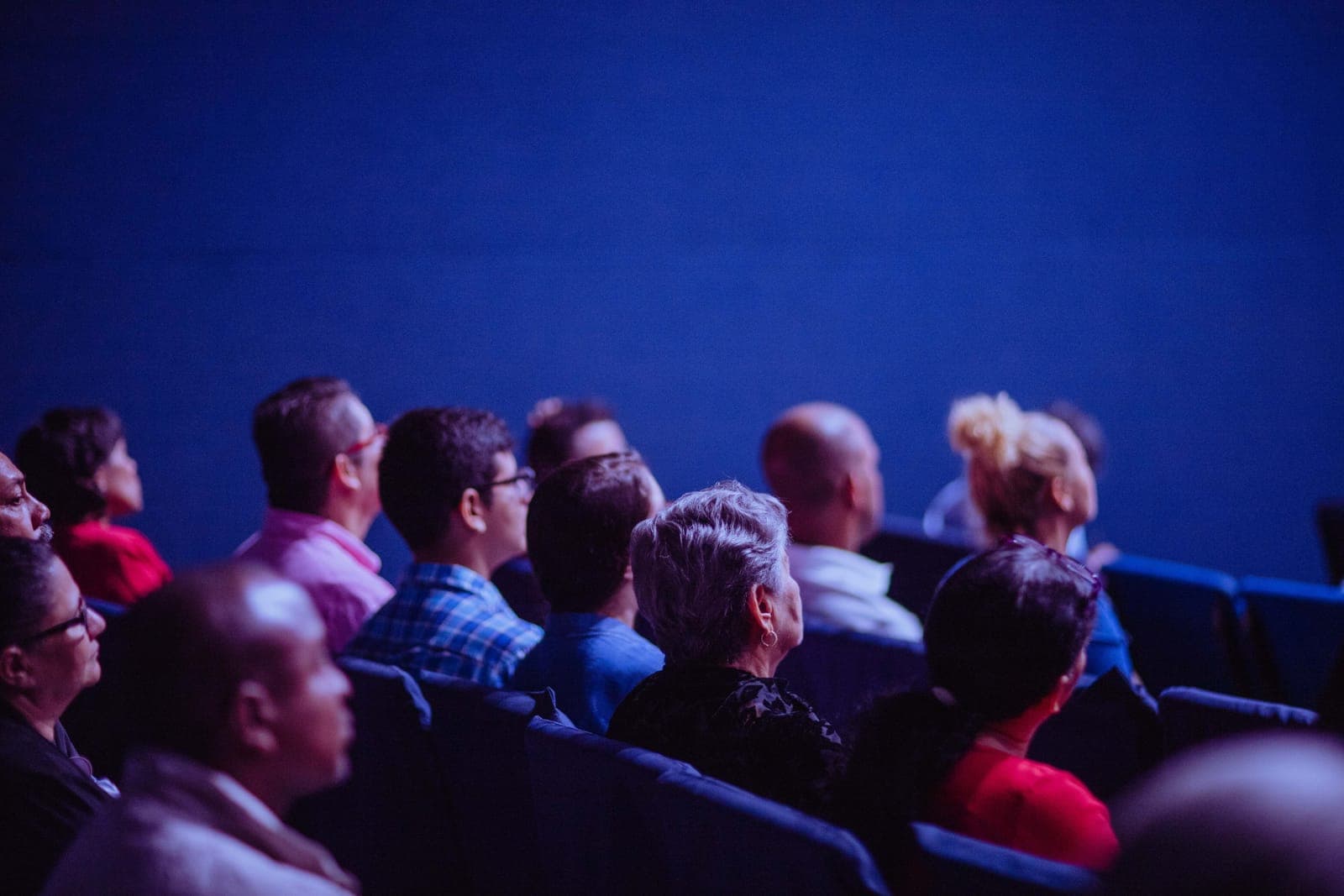 Audience members seated in rows during a presentation or keynote event with stage lighting.