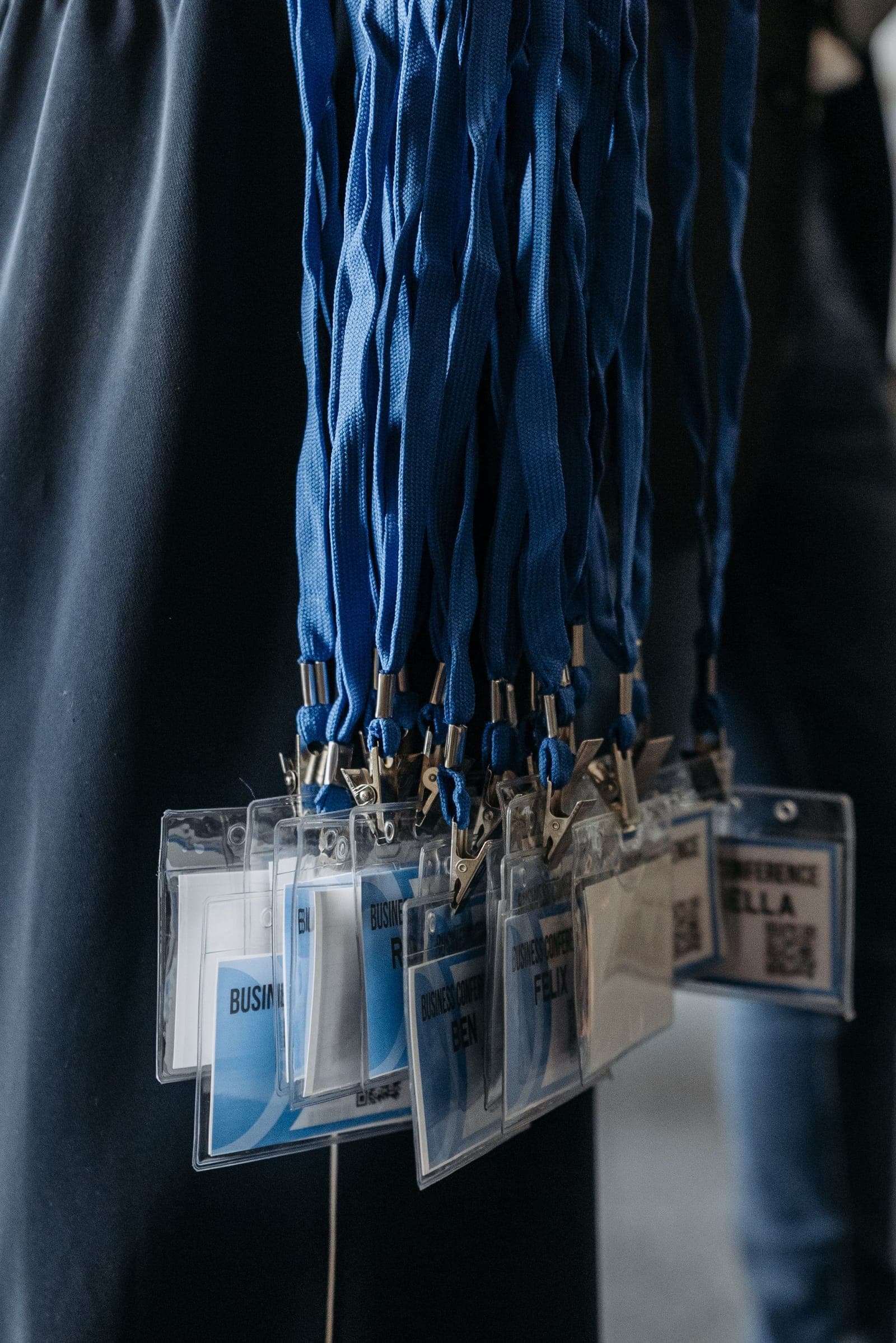 Close-up of multiple blue lanyards with clear plastic identification badges hanging from a person's clothing.
