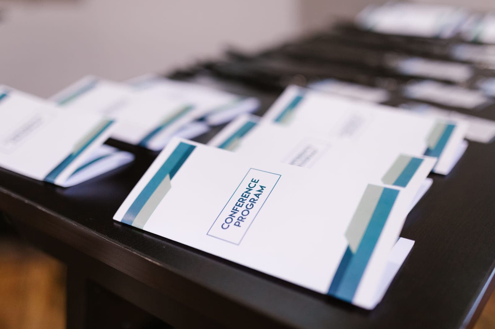 Multiple printed conference program booklets with blue accent stripes arranged in rows on a dark surface.
