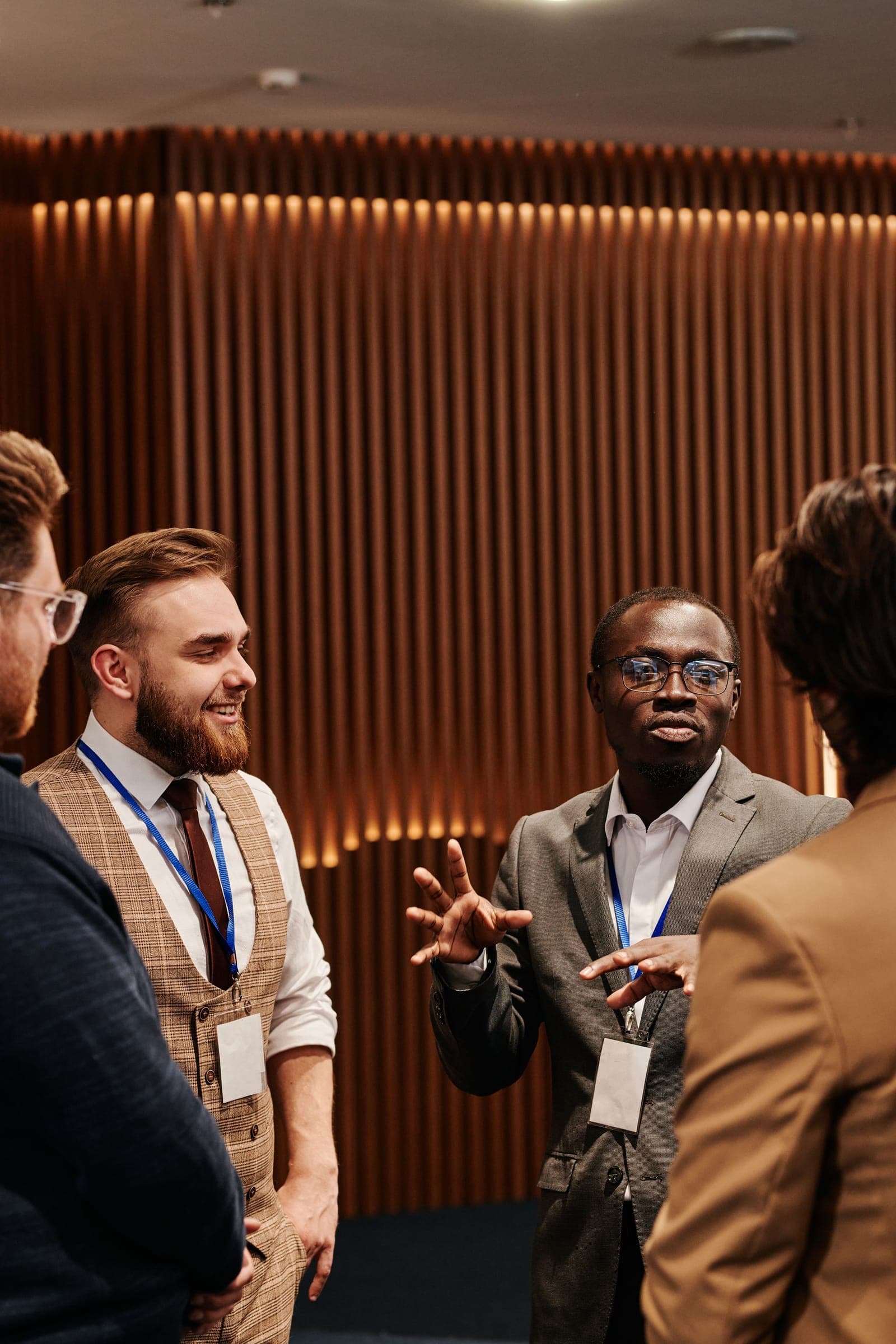 Professionals wearing conference badges engage in conversation at a networking event with modern interior.