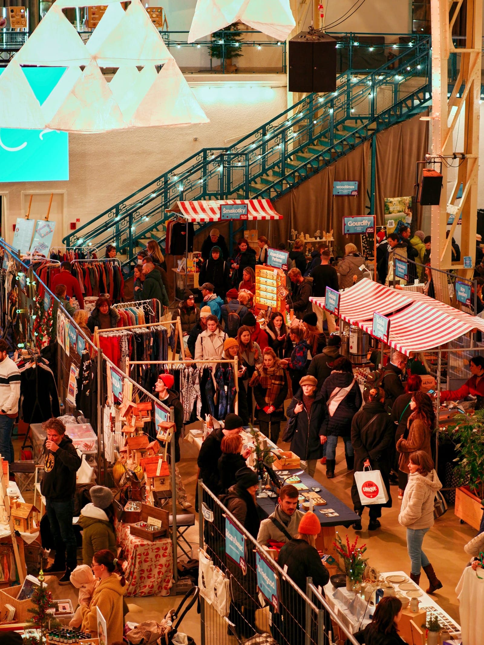 Overhead view of a busy trade show floor packed with attendees browsing multiple vendor booths with colorful striped awnings and signage.